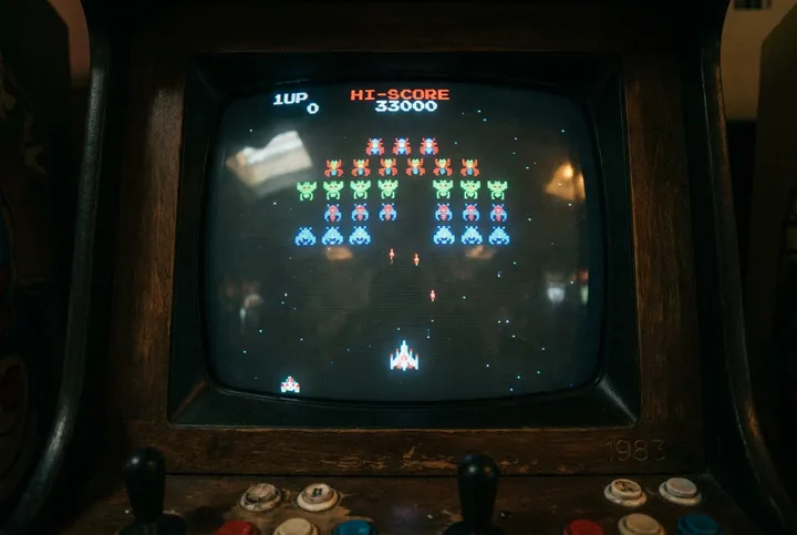 CRT arcade screen showing an 8-bit space shooter with 1UP and HI-SCORE readouts